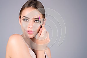 Beautiful woman applies brow gel with brows brush to her eyebrow. Studio portrait of young woman doing her eyebrow