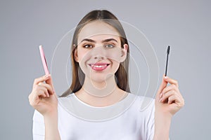Beautiful woman applies brow gel with brows brush to her eyebrow. Studio portrait of young woman doing her eyebrow