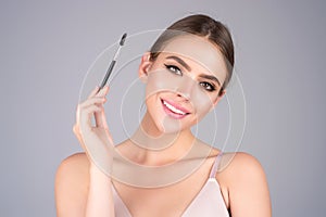 Beautiful woman applies brow gel with brows brush to her eyebrow. Studio portrait of young woman doing her eyebrow