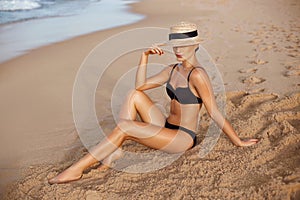 Beautiful Woman apply sun protection cream on her smooth tanned legs. Skin care. Legs on the beach. Portrait of female smearing mo
