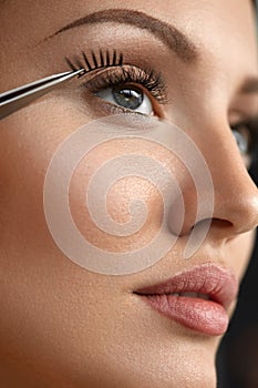 Beautiful Woman Applying Black Long Fake Eyelashes With Tweezers