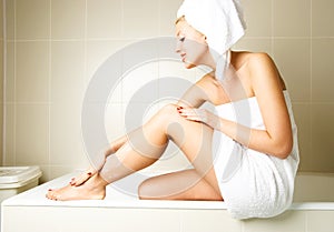 Beautiful woman applying body lotion photo