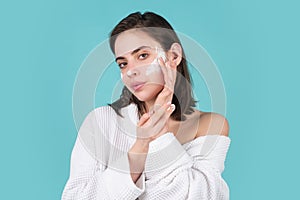 Beautiful woman applying cosmetic cream treatment on face. Skin care, close up face beauty portrait, isolated.