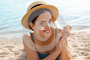 Beautiful woman applying cream sunscreen on tanned face. Sunscreen. Skin and body care