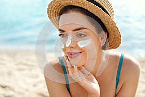 Beautiful woman applying cream sunscreen on a tanned face. Sunscreen. Skin and body care. The girl uses a sunscreen for her skin.