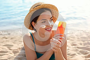 Beautiful woman applying cream sunscreen on tanned face. Sunscreen. Skin and body care. The girl uses a sunscreen for her skin.