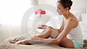 Beautiful woman applying cream to her legs at home