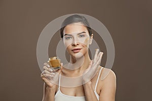 Beautiful woman applying cream to her skin. Facial treatment and skin care concept