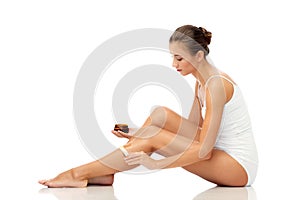 Beautiful woman applying depilatory wax to her leg