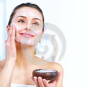 Beautiful woman applying facial mask