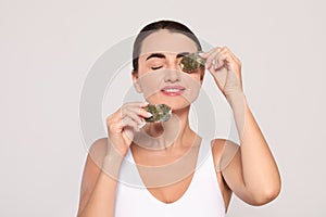 Beautiful woman applying green tea bags on skin under eyes against beige background