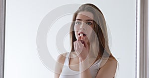 Beautiful woman applying lipstick, reflecting in big mirror