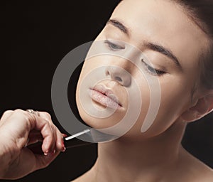 Beautiful woman applying makeup with a brush