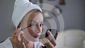 Beautiful woman is applying mascara on eyes. Girl apply make up on face