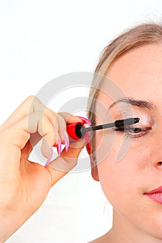 Beautiful woman applying mascara on her eyelashes