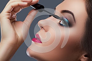 Beautiful woman applying mascara on her lashes