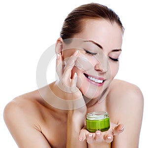 Beautiful woman applying moisturizer cream