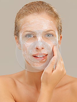 Beautiful woman applying moisturizer on her face