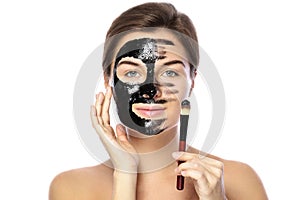 Beautiful woman is applying purifying black mask on her face