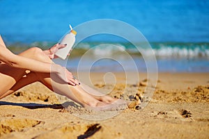 Beautiful woman applying sunscreen on her legs