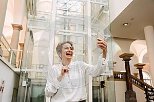 Beautiful woman art gallery manager using smartphone while standing in museum