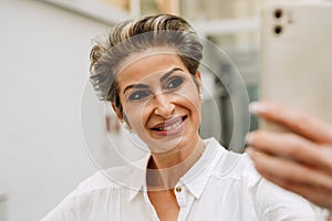 Beautiful woman art gallery manager using smartphone while standing in museum