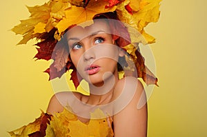 Beautiful woman with autumn leaves on yellow