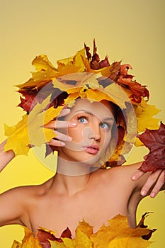 Beautiful woman with autumn leaves on yellow