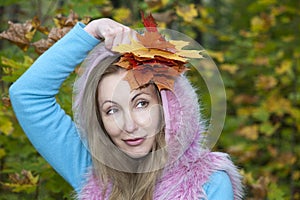 The beautiful woman in autumn park with maple leaves