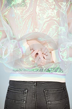 Beautiful woman back, hands and arms wearing a sweater with holographic effect, modern avantgarde artificial plastic look