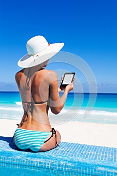 Beautiful woman from back reads ebook with hat