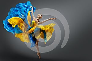 Beautiful Woman Ballet Dancer Jumping in Air in Colorful Fluttering Dress. Graceful Ballerina Dancing in Yellow Blue Gown