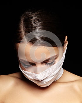 Beautiful woman with bandage mask on face. Fashion eye make-up. Beauty surgery or protection hygiene in virus pandemic