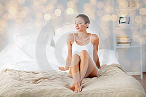 Beautiful woman with bare legs on bed at home