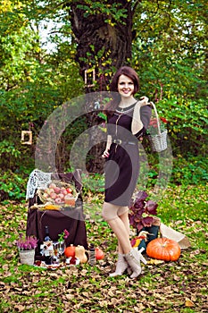 Beautiful woman with a basket of flowers in autumn park