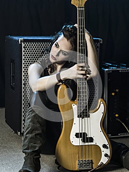 Beautiful woman bass player sitting with her amp