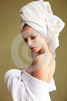 Beautiful woman in bath robe with a towel on her head looking thoughtfully into the camera