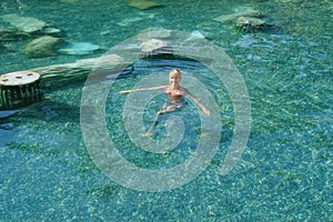 Beautiful woman bathing in a natural thermal pool