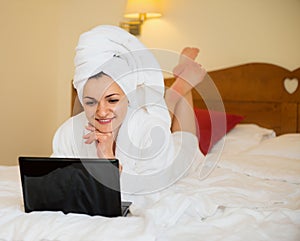 Beautiful woman in bathrobe with laptop