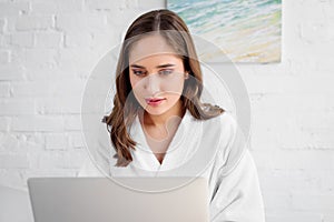 beautiful woman in bathrobe using laptop