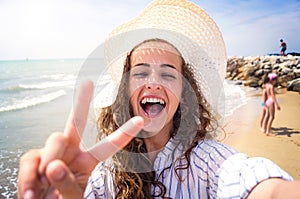 Beautiful woman on beach, laughing, taking selfie, sunny day