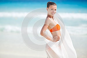 Beautiful woman on the beach in orange bikini