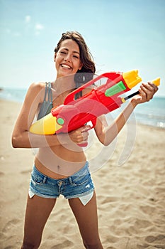 Beautiful woman on a beach with toy water gun
