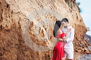 Beautiful woman and bearded man hugging near clay rock.