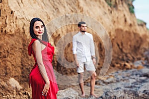 Beautiful woman and bearded man posing on the background of a clay rock.