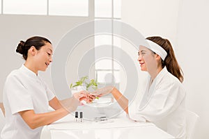 Beautiful woman with beautician applying nail varnish to female clients nails