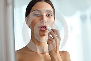 Beautiful Woman With Beauty Face Applies Balm On Lips. Skin Care photo