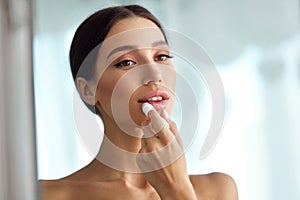 Beautiful Woman With Beauty Face Applies Balm On Lips. Skin Care photo