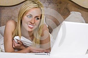 Beautiful Woman In Bed Using A Laptop Computer