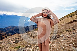 beautiful woman in beige clothes poses in the Caucasus Mountains in autumn. The wind blows the hair of attractive model
